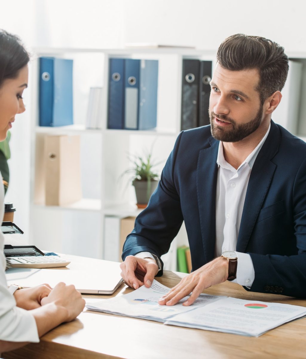 handsome advisor discussing document with investor at workspace